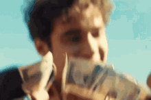 a man is holding a pile of money in front of his mouth .