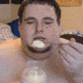 a man is eating something with a spoon from a bottle