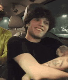 a man is sitting in the back seat of a car smiling .