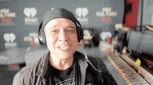 a man wearing headphones is smiling in front of a wall that has hearts on it