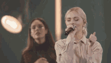 a woman singing into a microphone in front of a crowd at a concert