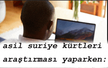 a man sitting in front of a laptop with the words asli suriye kurtleri