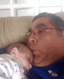 a man is kissing a baby on the cheek while wearing glasses