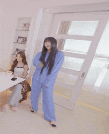 a woman in blue pajamas is standing next to another woman in white