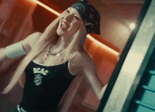 a woman wearing a bandana and a black tank top that says bcac