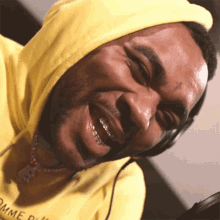 a man wearing a yellow comme des garçons hoodie smiles for the camera