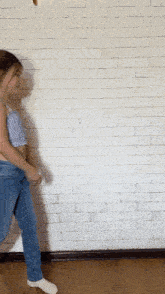 a little girl is standing in front of a brick wall