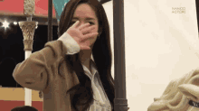 a woman covering her face in front of a banner that says namco actors