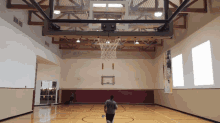 a man is playing basketball in a gym with a basketball net hanging from the ceiling