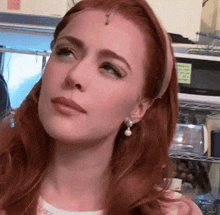 a woman with red hair wearing pearl earrings and a pink headband