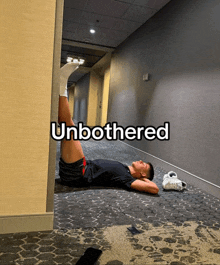 a man laying on the floor in a hallway with the word " unbothered " above him