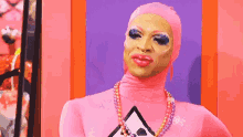 a drag queen wearing a pink bodysuit and a necklace