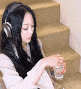 a woman wearing headphones and holding a glass of water