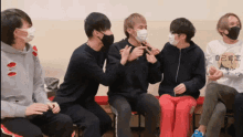 a group of young men wearing face masks are sitting in a room