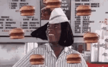 a man wearing a striped shirt and a hat is surrounded by hamburgers .