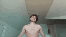 a shirtless man is sitting on a bed with his arms outstretched ..