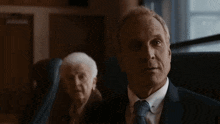 a man in a suit and tie is sitting next to an elderly woman and says you sure