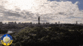 a statue on top of a hill with a city in the background