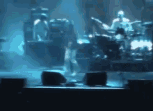 a man is playing drums on a stage in a dark room .