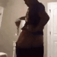 a man is standing in a bathroom without a shirt on and holding a towel .