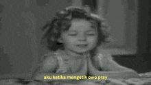 a black and white photo of a little girl praying with the words aku ketika mengetik owo pray above her