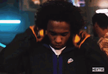 a man in a nike jacket adjusts his ear buds