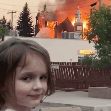 a young girl is standing in front of a burning church .