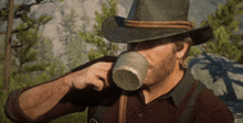 a man in a cowboy hat drinking from a cup