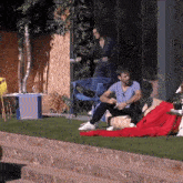 a man in a blue shirt sits on a red bean bag chair while a woman stands behind him