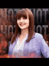 a woman in a purple jacket stands in front of a sign that says hot