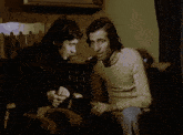 two men are sitting next to each other in a dark room and one is holding a cane