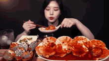 a woman is eating a plate of food with chopsticks and a spoon