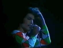 a man in a colorful shirt is singing into a microphone on a stage .