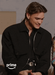 a man wearing a black jacket with the word prime on the bottom right