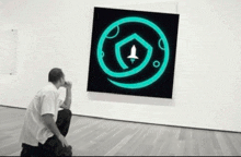 a man is kneeling down in front of a painting of a rocket on the moon