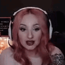 a woman with pink hair is wearing headphones and a tattoo on her arm .