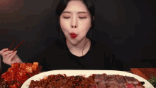a woman with chopsticks is eating a large plate of food .