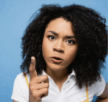 a woman with curly hair is pointing at the camera with her finger .