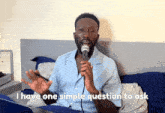 a man singing into a microphone with the words i have one simple question to ask behind him
