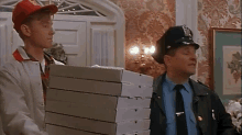a man carrying a stack of pizza boxes next to a policeman