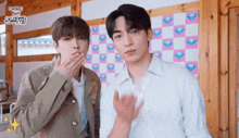 two young men are standing next to each other and one of them is covering his mouth with his hand