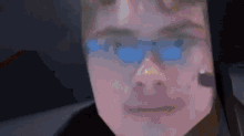 a close up of a man 's face with blue glasses