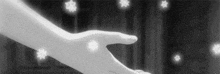 a black and white photo of two hands holding each other .