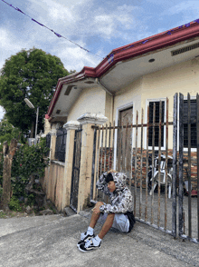 a person sitting on a sidewalk in front of a house