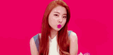 a woman with long red hair is blowing a kiss