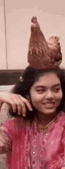 a girl with a chicken on her head is smiling .