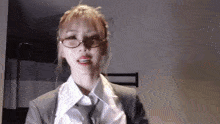 a woman in a suit and tie is wearing glasses and a white shirt .