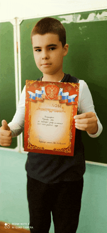 a young boy holds up a certificate that says aom on it