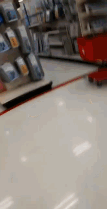 a person is pushing a red shopping cart through a store .