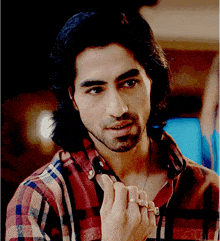 a man with long hair and a beard wearing a plaid shirt